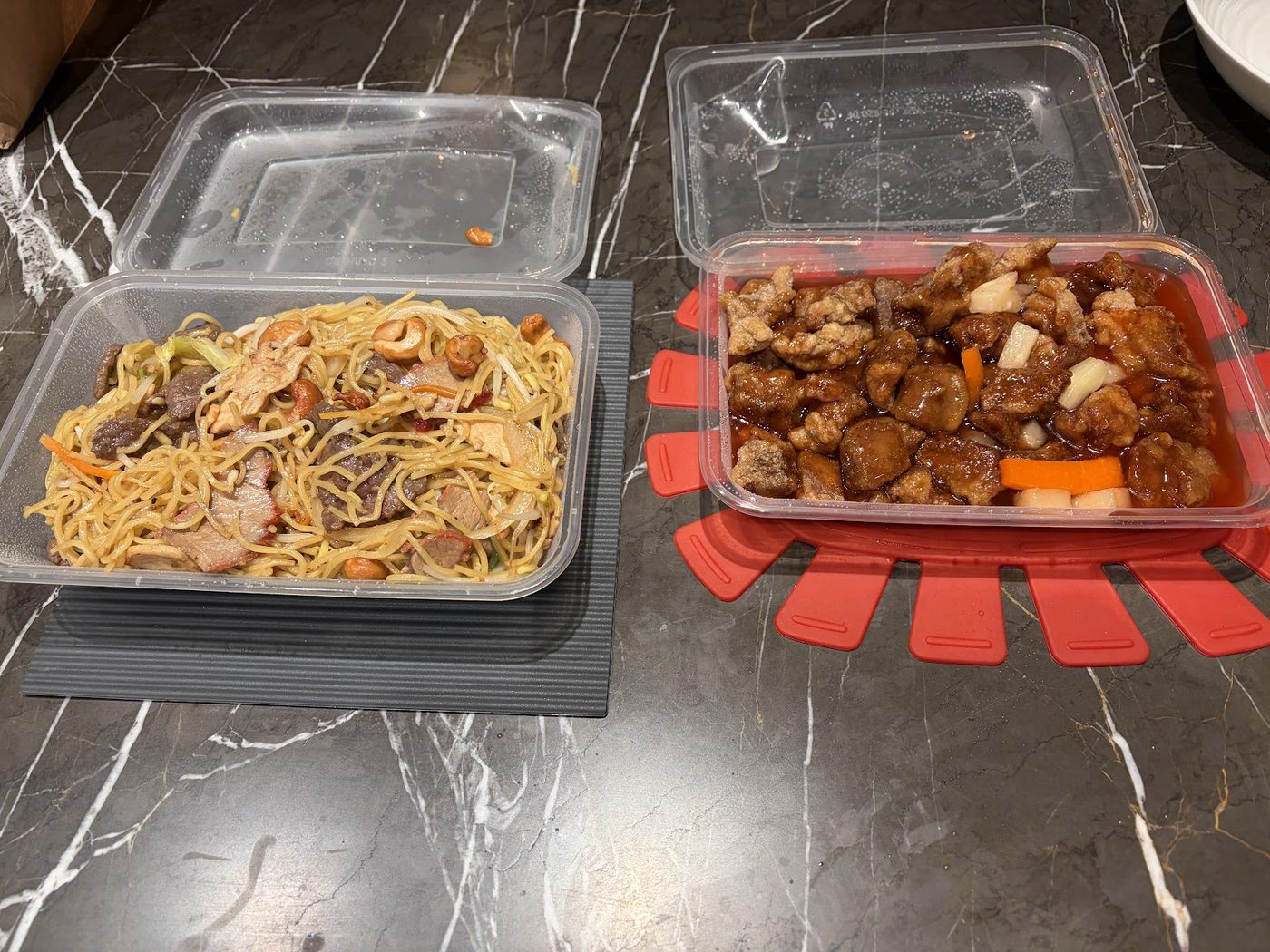 Two takeaway containers of noodles and sweet and sour pork